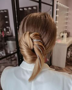 a woman with blonde hair in a ponytail wearing a white shirt and diamond headpiece