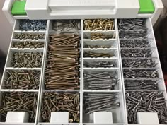 an organized drawer filled with lots of screws and nails in white plastic bins