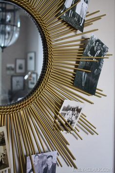 a round mirror hanging on the side of a wall next to pictures and photos in frames