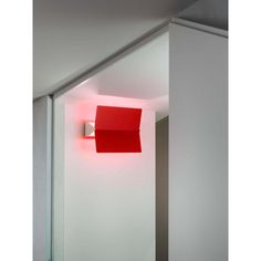 a red light that is on the side of a wall next to a white door