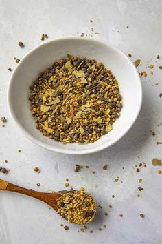 a white bowl filled with granola next to a wooden spoon on top of a table