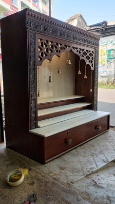 an elaborately carved wooden bench with bells hanging from it's sides and drawers