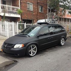 a black car parked in front of a house with a bike on top of it