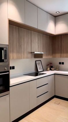 a modern kitchen with white cabinets and wood flooring on the countertop, along with an oven