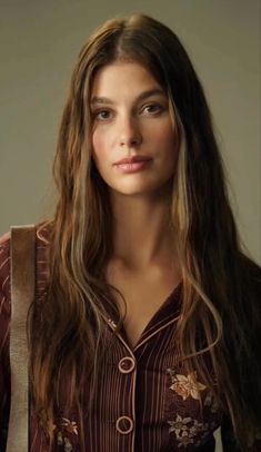 a woman with long brown hair is looking at the camera