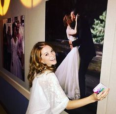 a bride and groom standing in front of pictures on the wall at their wedding reception