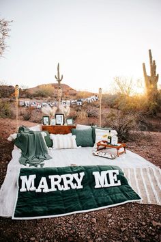 a green and white blanket sitting on top of a bed in the middle of a desert