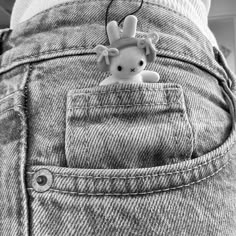 a small stuffed animal sticking out of the back pocket of someone's jean pants