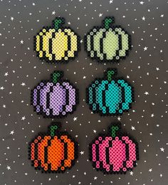 four pixellated pumpkins are shown on a black surface with stars in the background