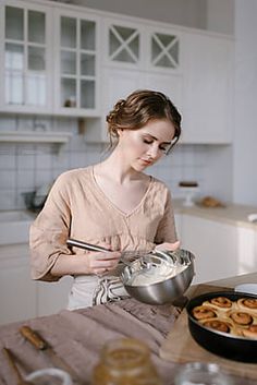 a woman is mixing food in a bowl on the kitchen counter with pretzels