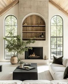 a living room filled with furniture and a fire place in the middle of two windows