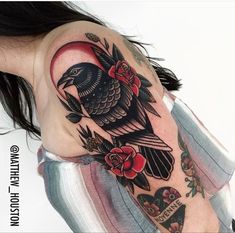 a woman's shoulder with a bird and roses tattoo on it