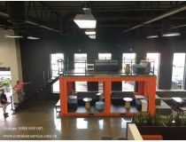 an empty room with tables and stools in it, people are walking around the area