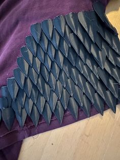 a purple shirt with black spikes on the front and back of it sitting on a wooden floor