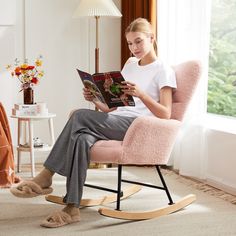 a woman sitting in a pink rocking chair reading a book while wearing slip ons