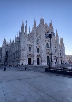 a large cathedral with many spires on it's sides and people walking around