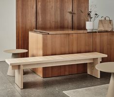 a wooden bench sitting in front of a cabinet next to a white table and chair