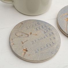 two old coins with writing on them next to a cup