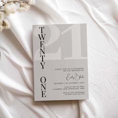 a white and black wedding card with the number twenty one on it next to some flowers