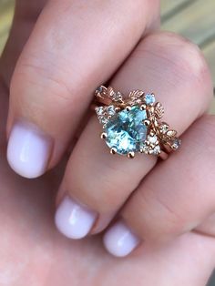 a close up of a person's hand holding a ring with an aqua blue stone