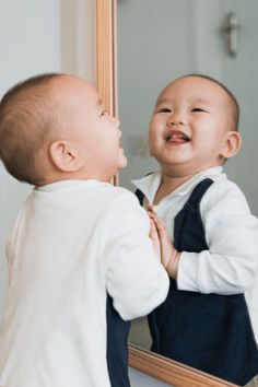 a baby is looking at himself in the mirror