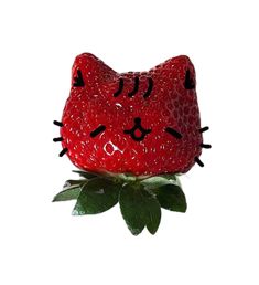 a strawberry shaped like a cat sitting on top of a green leafy plant in front of a white background