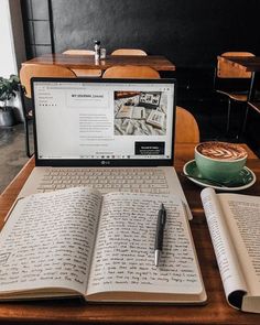 an open laptop computer sitting on top of a wooden table next to a cup of coffee