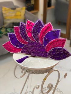 a purple and pink headpiece sitting on top of a white table next to a couch