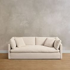 a white couch sitting on top of a hard wood floor next to a gray wall