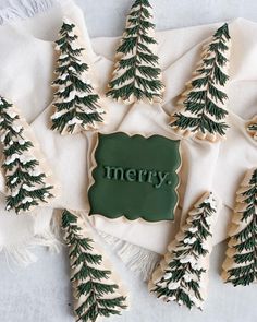 christmas cookies decorated with green and white icing are sitting on a napkin next to small trees