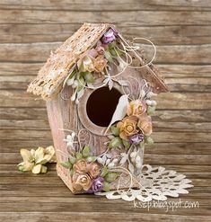 a birdhouse with flowers on the outside and a lace doily around it's edge