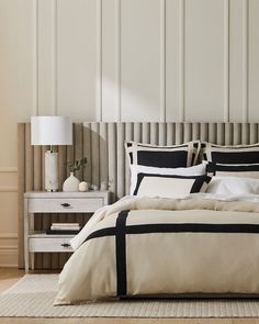 a bed with black and white comforters in a neutral room next to a nightstand