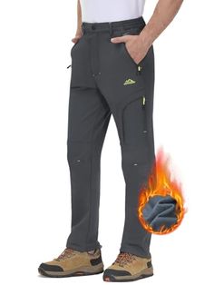 a man standing in front of a white background wearing grey pants with flames on the side