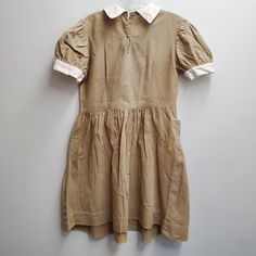 "This vintage dress is truly adorable! This dress is cotton and is a lovely camel brown color. The dress has a white pique collar and short sleeves with coordinating cuffs. There is a panel down the front with embroidered lace for a slightly more fancy look. The dress buttons down the back and has pockets on the front with white piping around. Truly this is a lovely dress. NOTE: there are a few areas with hand-stitching on the side seams. No holes or problems but charming repair work. Length = ( Classic Party Dress, Sailor Shirt, Classic Party, Dress Buttons, Sailor Dress, White Details, Childrens Dress, Sweet Tea, Button Dress