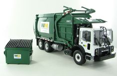 a green and white garbage truck next to a trash can on a white table top