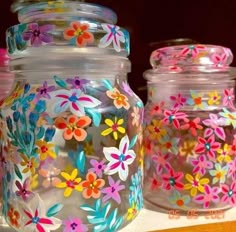 three glass jars with painted flowers on them