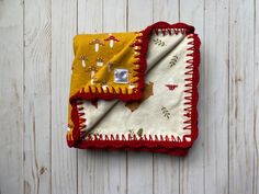 a yellow and red blanket sitting on top of a white wooden table next to a pair of scissors