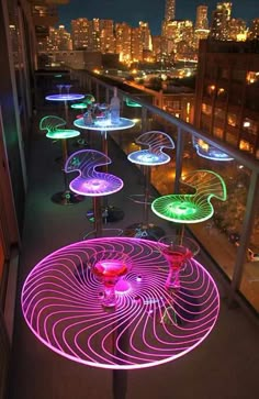 colorful lights on the outside of an apartment building at night, with city lights in the background