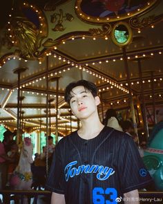 a young man standing in front of a carousel