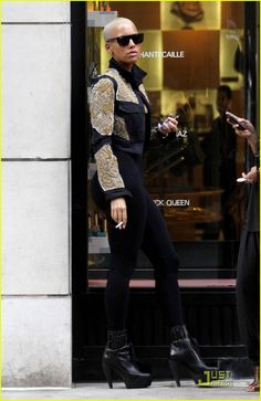 a woman in black and gold outfit walking down the street with her hand on her hip