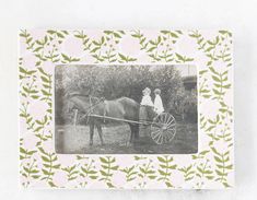 an old photo of two people sitting on a horse drawn carriage in front of trees