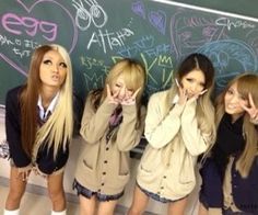 four girls standing in front of a chalkboard with their hands on their face and looking at the camera