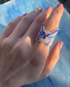 a woman's hand with a ring on it that has an origami star in the middle