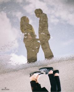 two people standing in the sand with their feet up and one person's reflection behind them