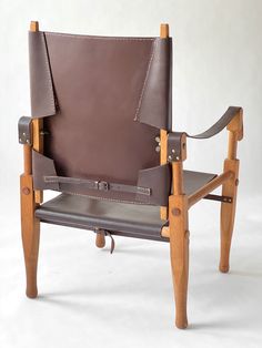 a brown leather chair with wooden legs and armrests on a white background,