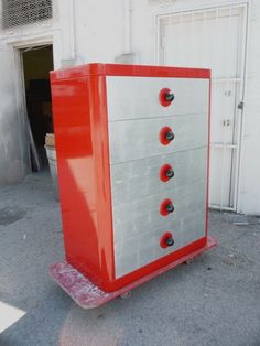 a red and silver dresser sitting in front of a white building