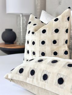 two black and white pillows sitting on top of a bed next to a night stand