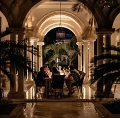 some people are sitting at a table in the middle of an archway with lights on