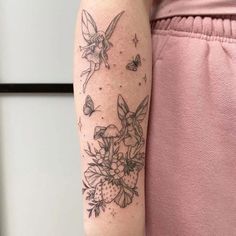 a woman's arm with flowers and butterflies tattooed on the back of her left arm