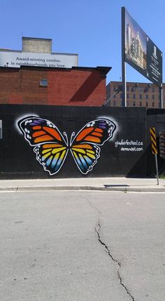 an orange and black butterfly painted on the side of a building next to a street